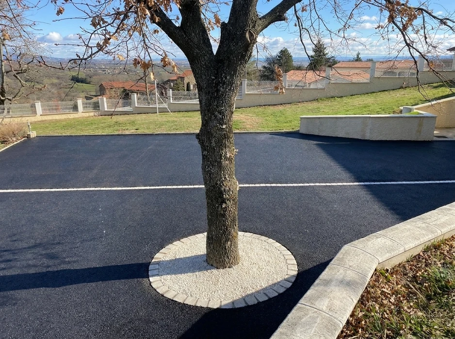 Allée privative en enrobé bitumineux noir fraîchement posé, avec bordures en pavés de béton