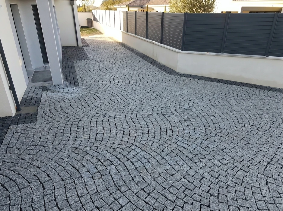 Allée extérieure pavée en granit gris, motif en éventail ondulé, bordures sombres de délimitation