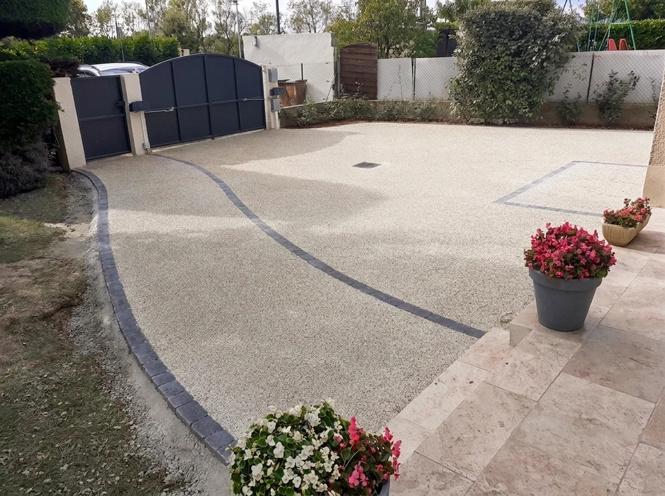 Allée de maison avec revêtement en gravillon résine (béton drainant), bordures en pavés de granit anthracite, ligne décorative courbe en pavés